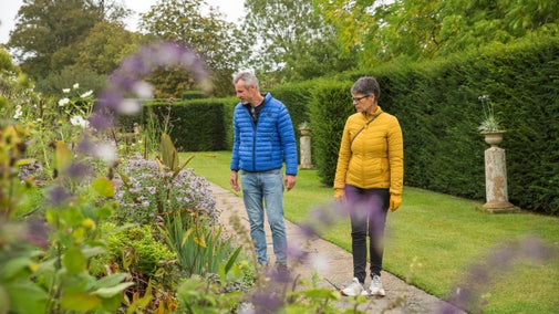 Two visitors looking at a long border in the garden at Lytes Cary Manor